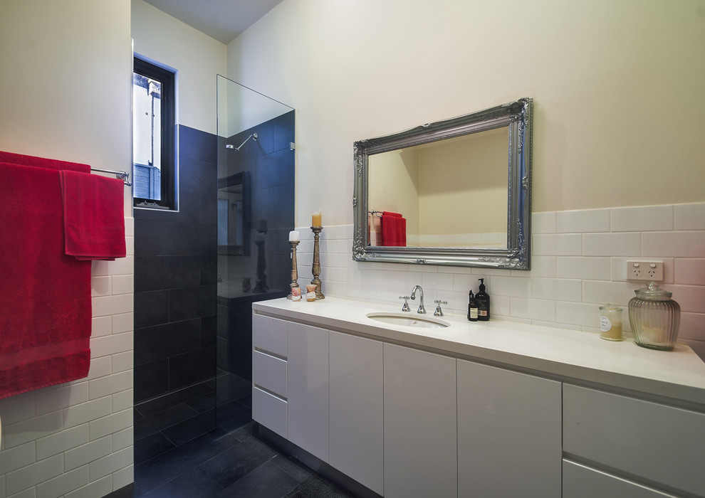 Photo of a mid-sized contemporary kids bathroom in Melbourne with flat-panel cabinets, white cabinets, a claw-foot tub, an alcove shower, a one-piece toilet, white tile, ceramic tile, white walls, porcelain floors, an undermount sink, engineered quartz benchtops, grey floor and an open shower.