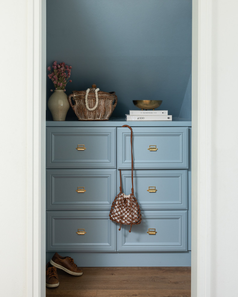 Aménagement d'une petite armoire encastrée avec des portes de placard bleues et un sol en bois brun.
