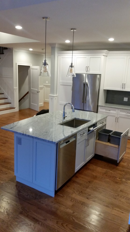 Photo of a mid-sized traditional l-shaped eat-in kitchen in Boston with an undermount sink, shaker cabinets, white cabinets, granite benchtops, grey splashback, glass tile splashback, stainless steel appliances, medium hardwood floors and with island.
