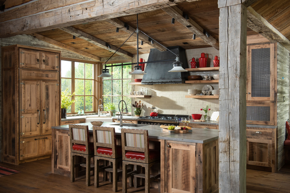 Example of a mountain style l-shaped medium tone wood floor kitchen design with a farmhouse sink, shaker cabinets, distressed cabinets, beige backsplash, subway tile backsplash, an island and gray countertops