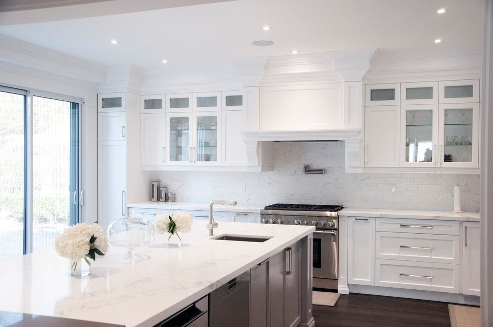 Inspiration for a large transitional l-shaped dark wood floor and brown floor enclosed kitchen remodel in Toronto with an undermount sink, shaker cabinets, white cabinets, quartz countertops, white backsplash, marble backsplash, stainless steel appliances, an island and white countertops