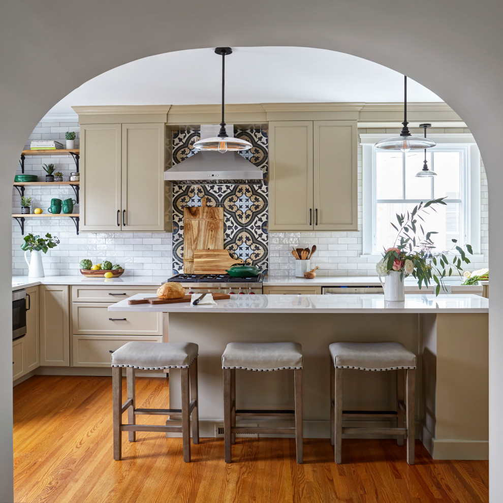 Design ideas for a traditional u-shaped separate kitchen in Chicago with a farmhouse sink, shaker cabinets, beige cabinets, quartzite benchtops, multi-coloured splashback, porcelain splashback, stainless steel appliances, medium hardwood floors, with island and beige benchtop.