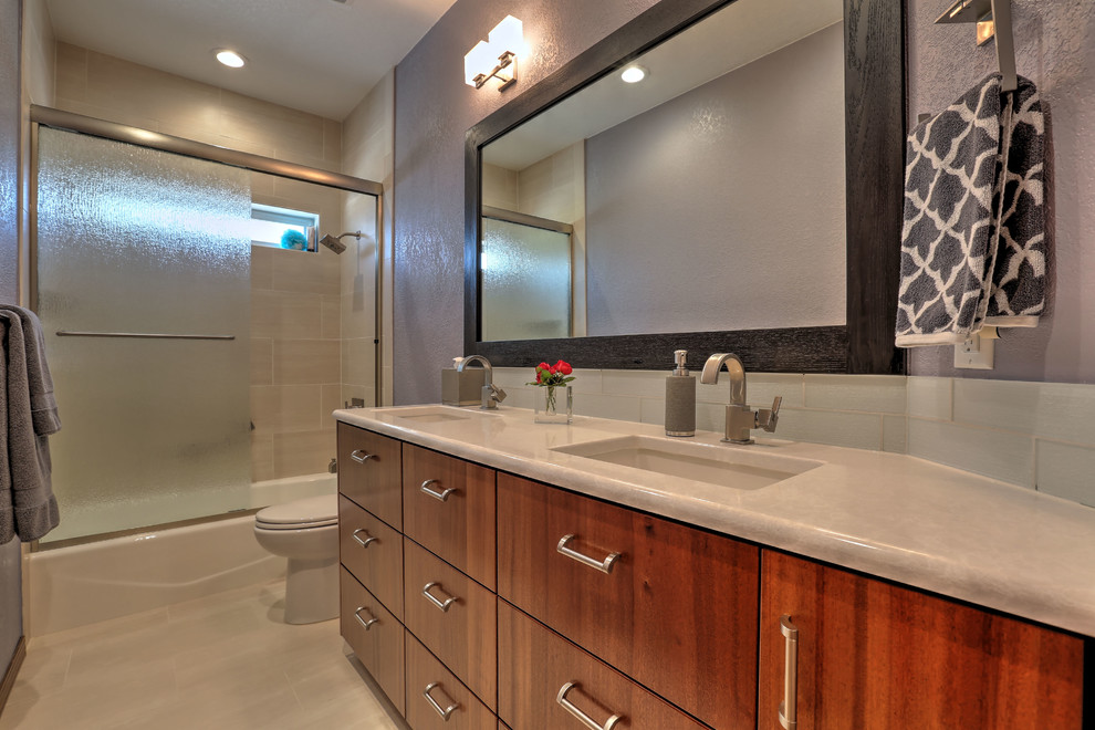 Mid-sized modern 3/4 bathroom in Seattle with flat-panel cabinets, medium wood cabinets, an alcove tub, a shower/bathtub combo, a two-piece toilet, white tile, glass tile, purple walls, porcelain floors, an undermount sink, laminate benchtops, beige floor and a sliding shower screen.