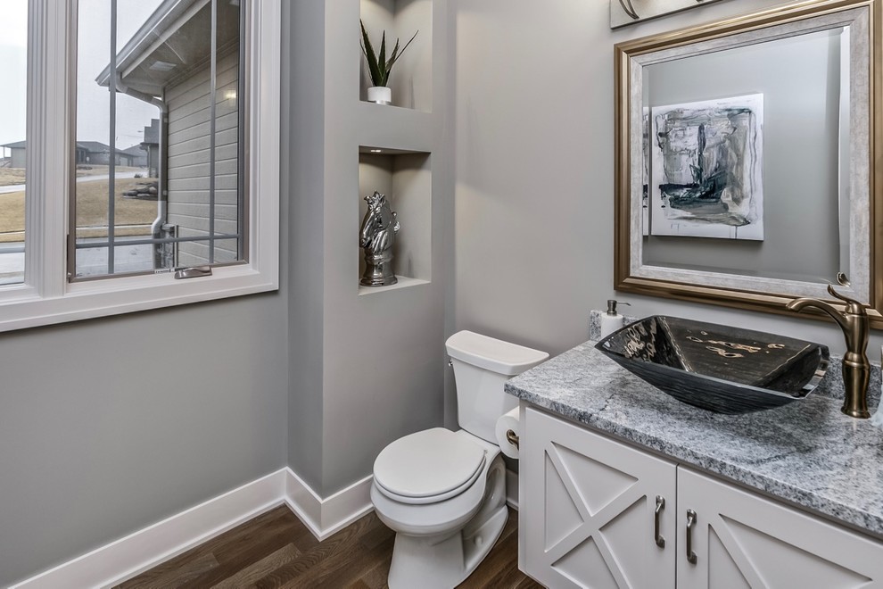 Mid-sized transitional powder room in Omaha with shaker cabinets, a two-piece toilet, grey walls, light hardwood floors, a vessel sink and granite benchtops.