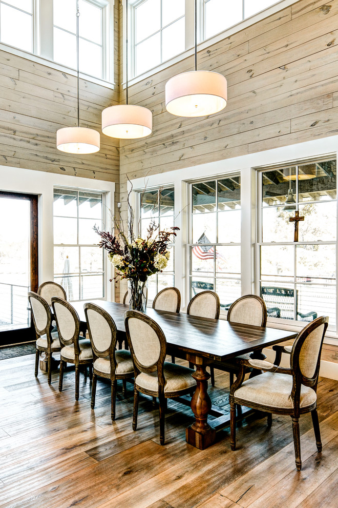 This is an example of a country open plan dining in Austin with light hardwood floors.