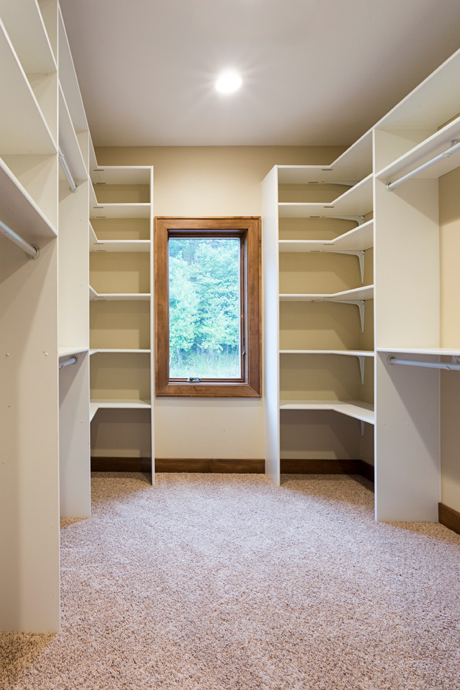 Photo of a large arts and crafts gender-neutral walk-in wardrobe in Other with open cabinets, white cabinets and carpet.