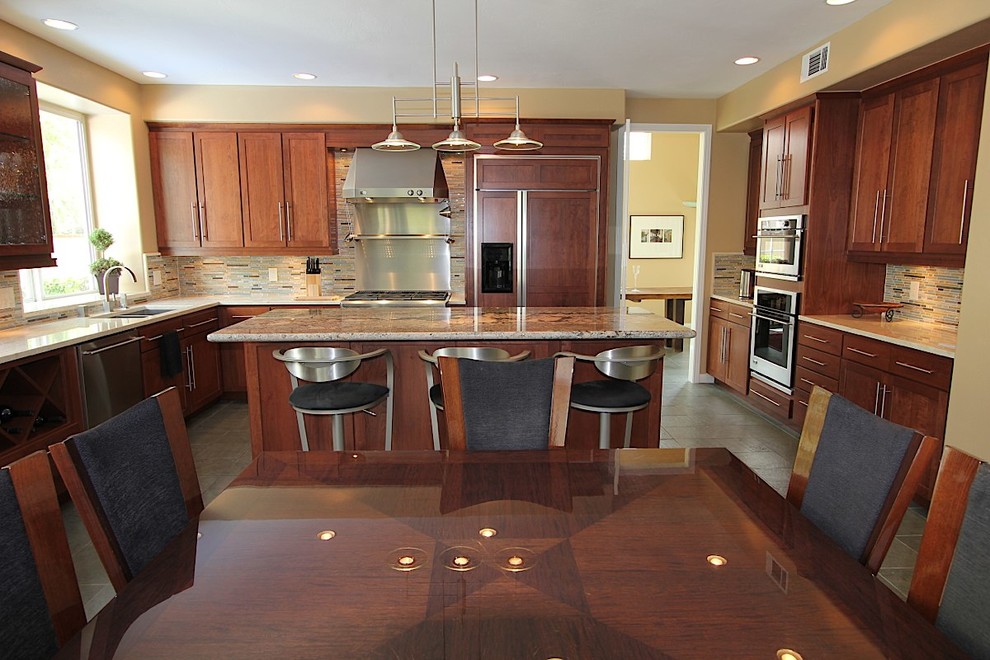 Large transitional l-shaped slate floor kitchen photo with an undermount sink, recessed-panel cabinets, medium tone wood cabinets, granite countertops, multicolored backsplash, matchstick tile backsplash, stainless steel appliances and an island