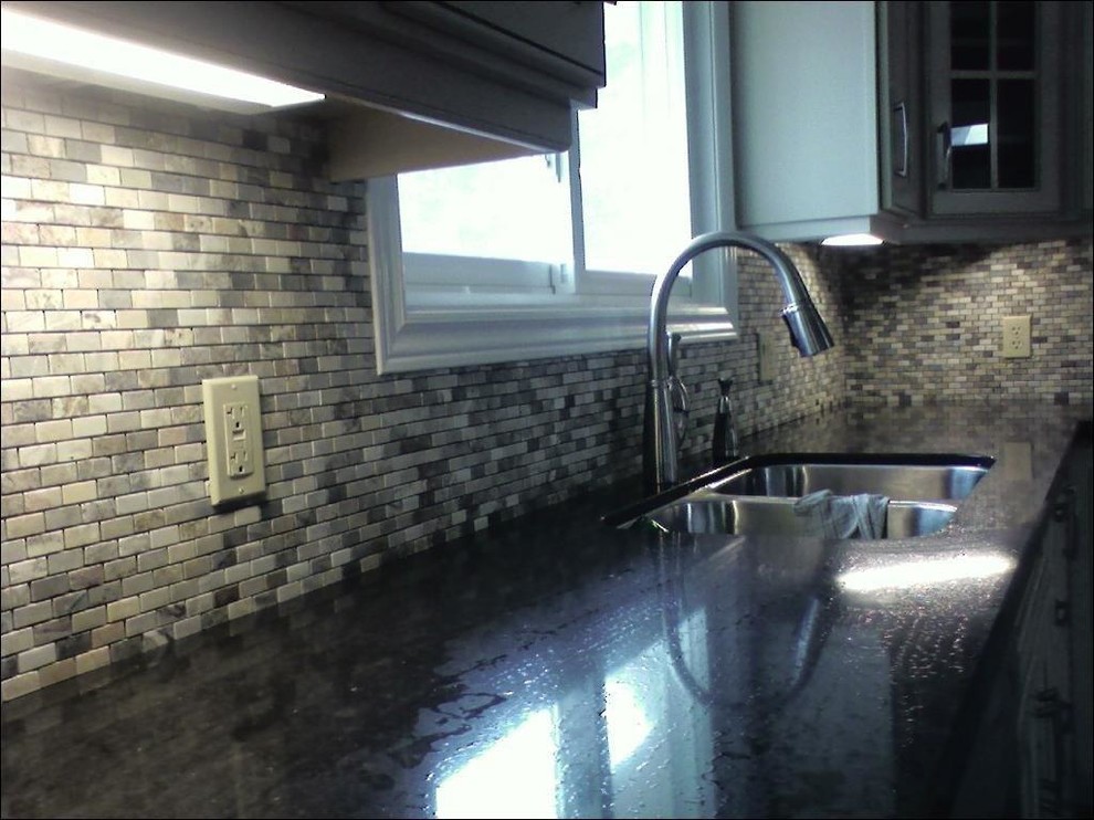 This is an example of a traditional eat-in kitchen in Toronto with multi-coloured splashback and stone tile splashback.