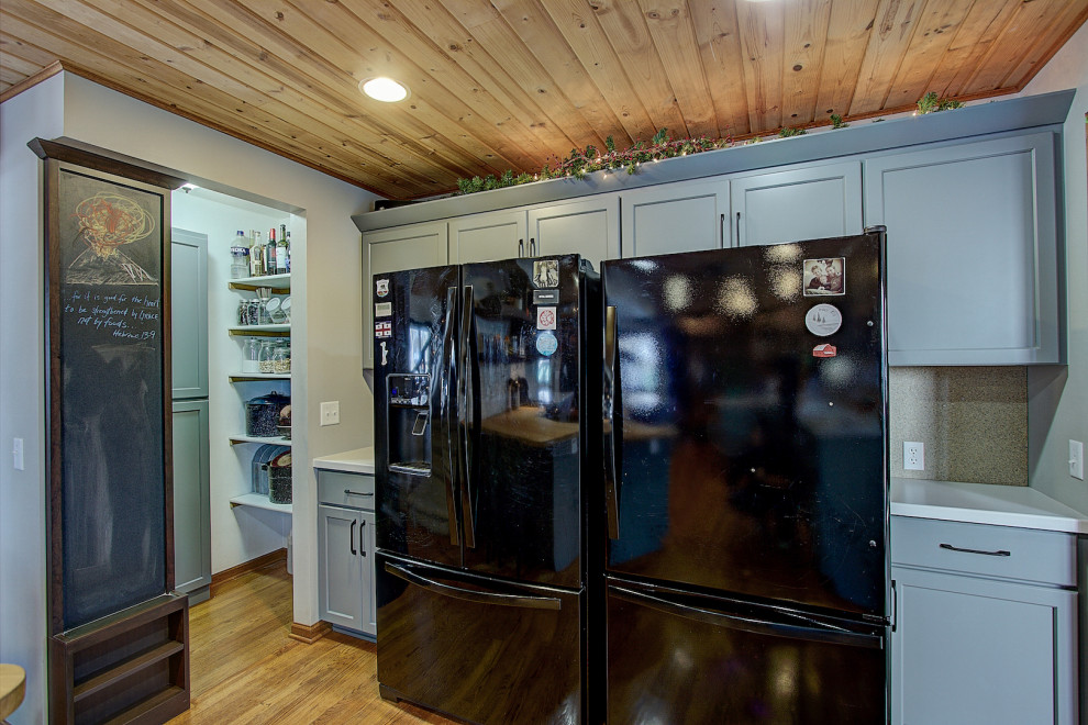 Inspiration for a mid-sized transitional galley medium tone wood floor and brown floor eat-in kitchen remodel with an undermount sink, shaker cabinets, gray cabinets, quartz countertops, gray backsplash, stone tile backsplash, black appliances, a peninsula and white countertops