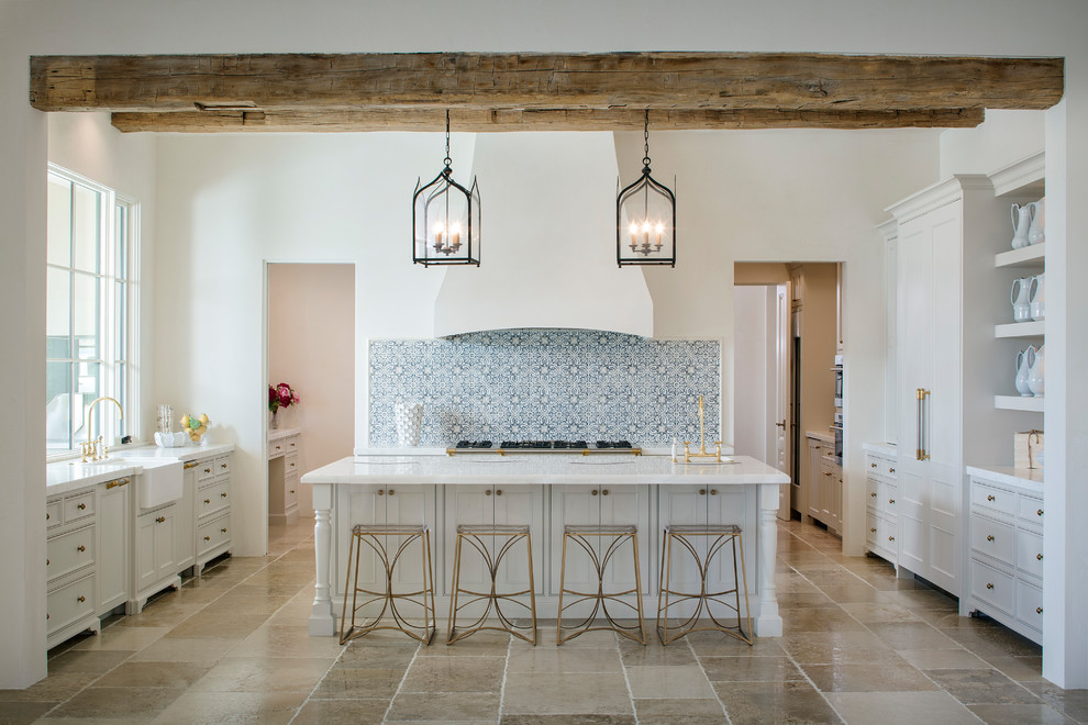 Photo of a mediterranean u-shaped open plan kitchen in Los Angeles with a farmhouse sink, recessed-panel cabinets, white cabinets, blue splashback, white appliances, travertine floors, with island and beige floor.