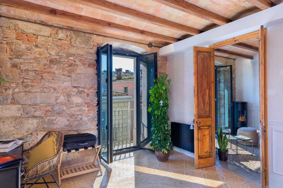 Foto de dormitorio principal clásico renovado con paredes grises, suelo de baldosas de cerámica, estufa de leña, suelo amarillo, vigas vistas y ladrillo