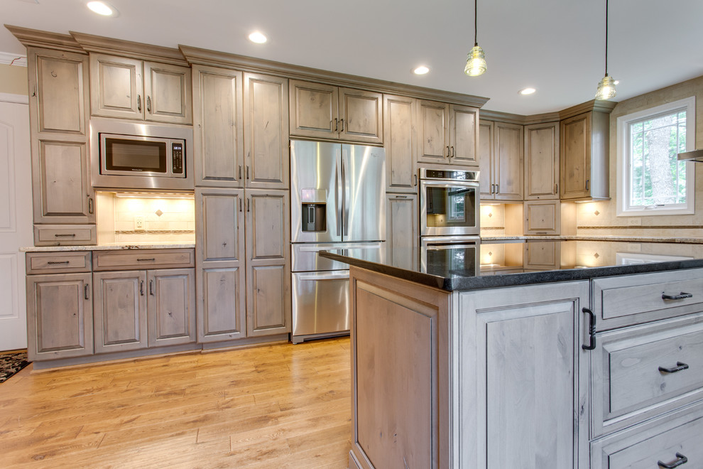 Inspiration for a large country l-shaped kitchen in DC Metro with a farmhouse sink, raised-panel cabinets, granite benchtops, ceramic splashback, stainless steel appliances, medium hardwood floors and with island.