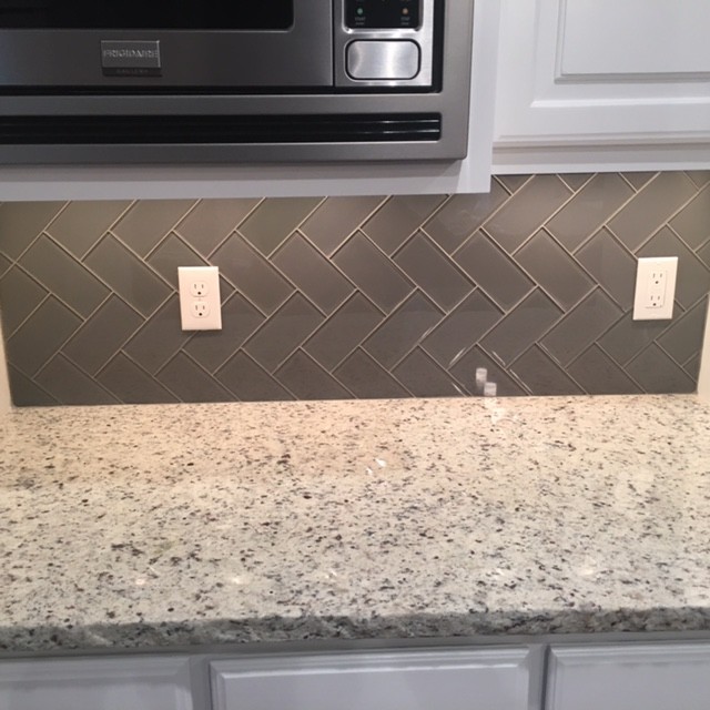Enclosed kitchen - mid-sized transitional galley brick floor and gray floor enclosed kitchen idea with an undermount sink, raised-panel cabinets, white cabinets, wood countertops, gray backsplash, glass tile backsplash, stainless steel appliances and an island