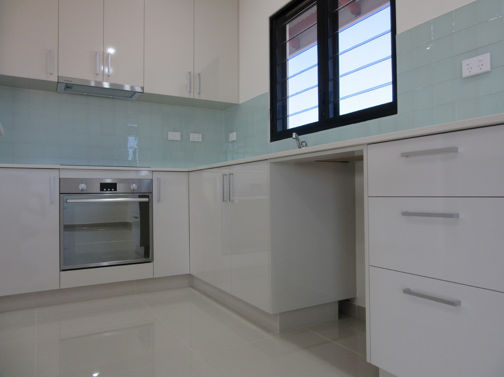 Mid-sized modern l-shaped kitchen in Darwin with white cabinets, granite benchtops, blue splashback, glass tile splashback, stainless steel appliances and with island.