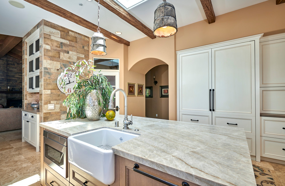 Inspiration for a mid-sized rustic galley travertine floor, beige floor and exposed beam open concept kitchen remodel in Denver with a farmhouse sink, recessed-panel cabinets, white cabinets, quartz countertops, multicolored backsplash, stone tile backsplash, stainless steel appliances, an island and brown countertops