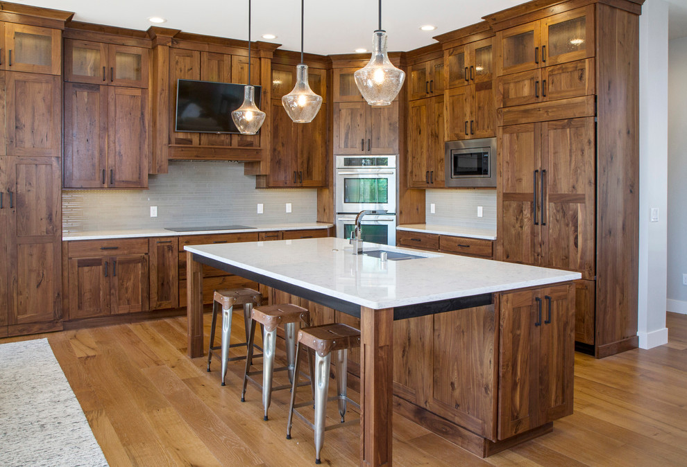Inspiration for a large traditional l-shaped open plan kitchen in Other with an undermount sink, shaker cabinets, dark wood cabinets, quartz benchtops, grey splashback, glass tile splashback, stainless steel appliances, light hardwood floors and with island.