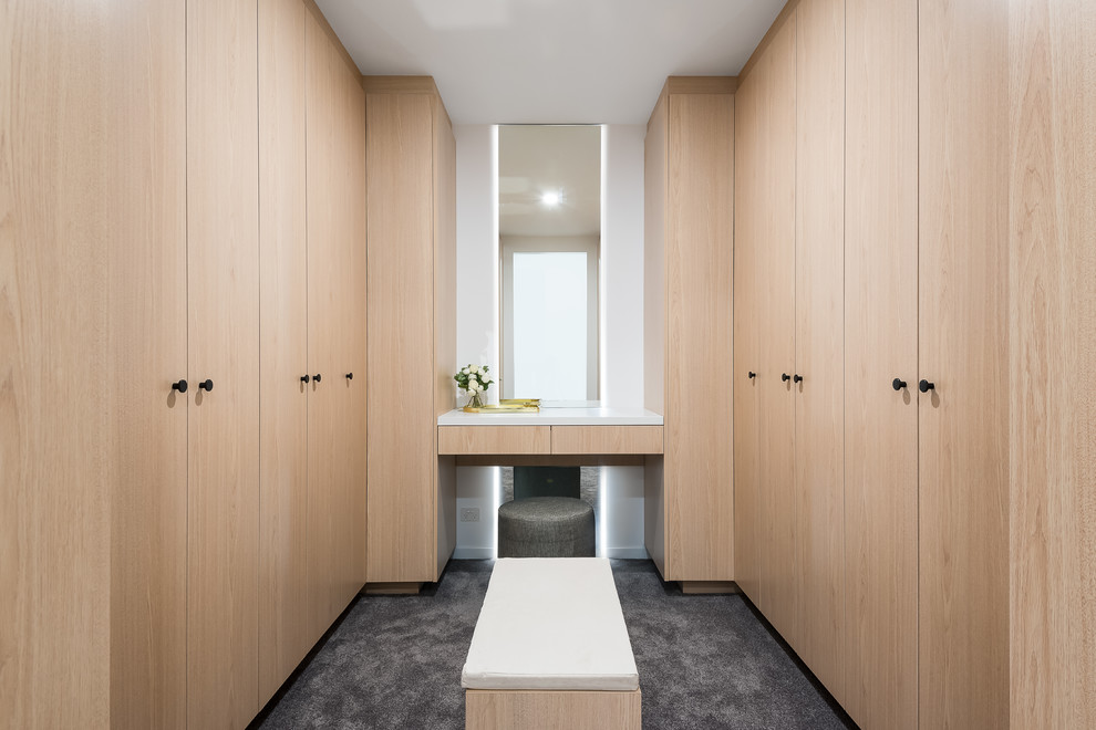 This is an example of a large contemporary gender-neutral walk-in wardrobe in Brisbane with light wood cabinets and carpet.