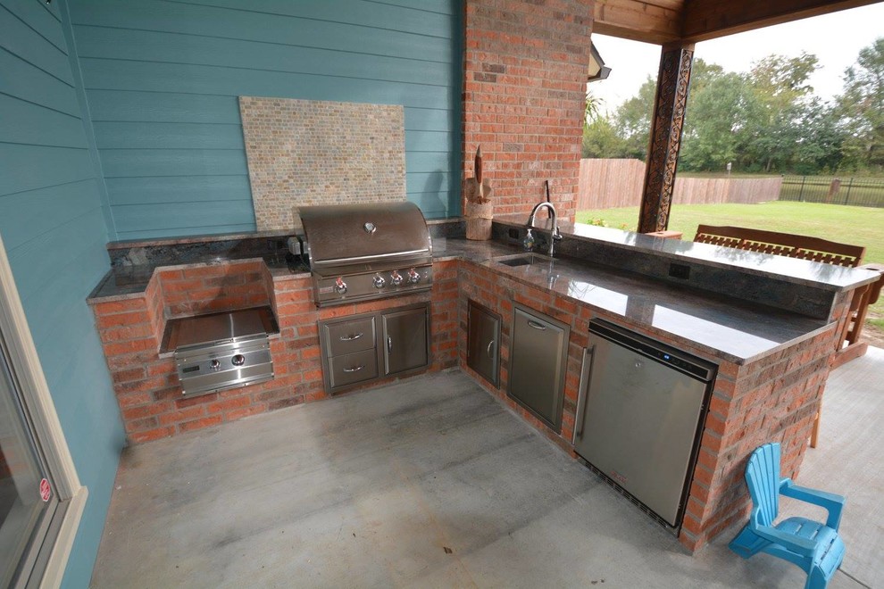 Mid-sized country backyard patio in New Orleans with an outdoor kitchen, concrete slab and a roof extension.