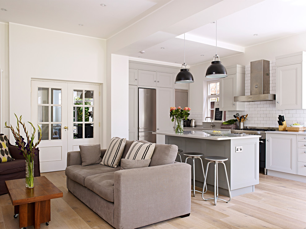 Design ideas for a mid-sized contemporary open plan kitchen in London with grey cabinets, with island, a drop-in sink, shaker cabinets, quartzite benchtops, white splashback, ceramic splashback and stainless steel appliances.