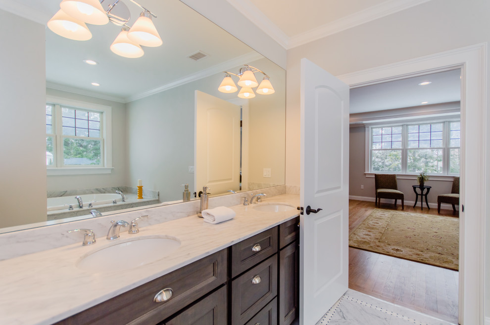 This is an example of a mid-sized transitional bathroom in Boston with brown cabinets, an alcove tub, a shower/bathtub combo, a two-piece toilet, white tile, ceramic tile, beige walls, ceramic floors, an undermount sink and engineered quartz benchtops.