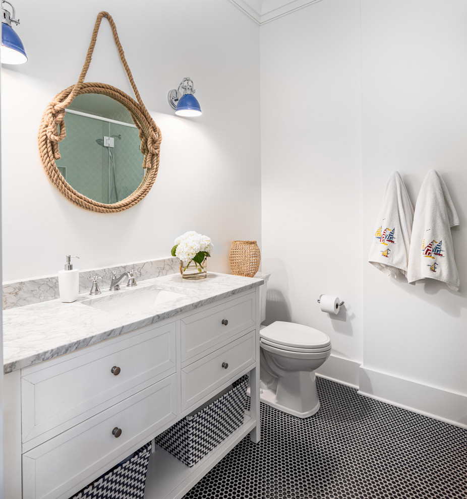Photo of a beach style bathroom in Charleston with a two-piece toilet, white walls, an undermount sink, white cabinets, mosaic tile floors, black floor, grey benchtops and recessed-panel cabinets.