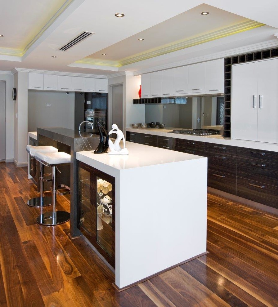 Photo of a large modern galley kitchen in Perth with a double-bowl sink, flat-panel cabinets, brown cabinets, quartz benchtops, metallic splashback, mirror splashback, stainless steel appliances, light hardwood floors, no island, brown floor, white benchtop and recessed.