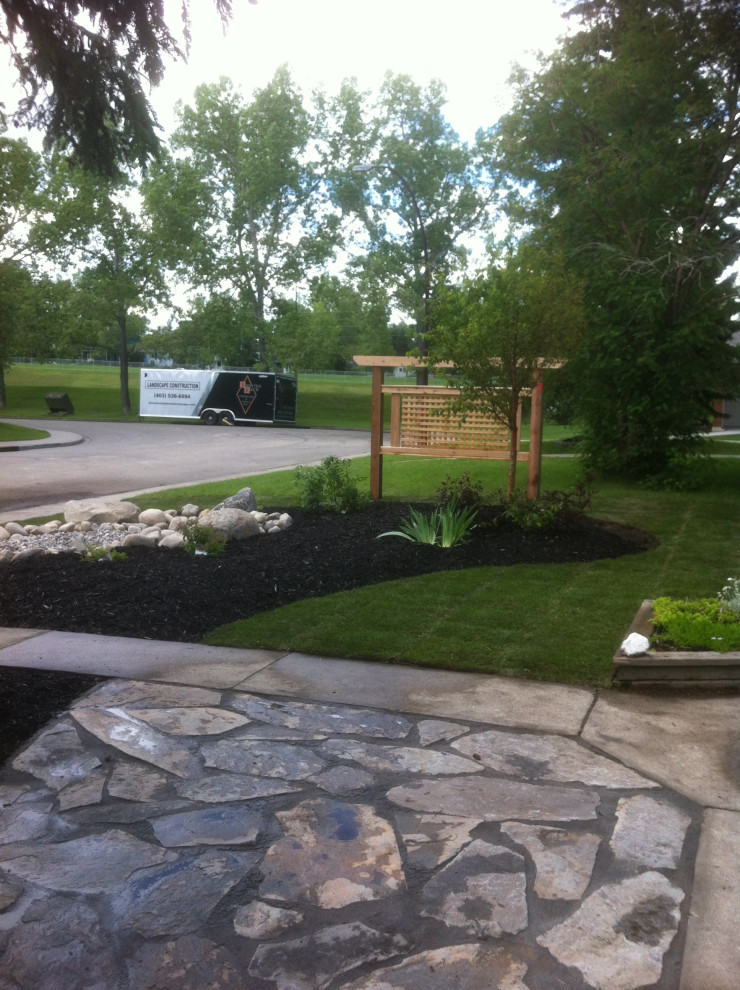 Inspiration for a small front yard formal garden in Calgary with with privacy feature and natural stone pavers.