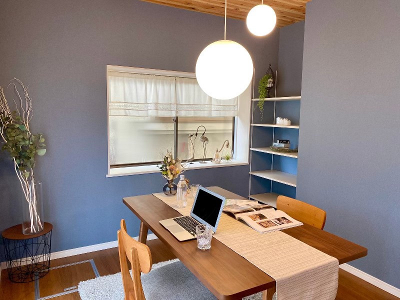 Cette image montre une salle à manger avec un mur bleu, un sol en contreplaqué, un sol marron, un plafond en papier peint et du papier peint.