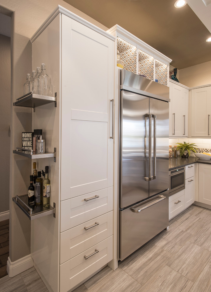 Example of a mid-sized transitional u-shaped porcelain tile open concept kitchen design in Phoenix with a farmhouse sink, shaker cabinets, white cabinets, solid surface countertops, white backsplash, subway tile backsplash, stainless steel appliances and an island
