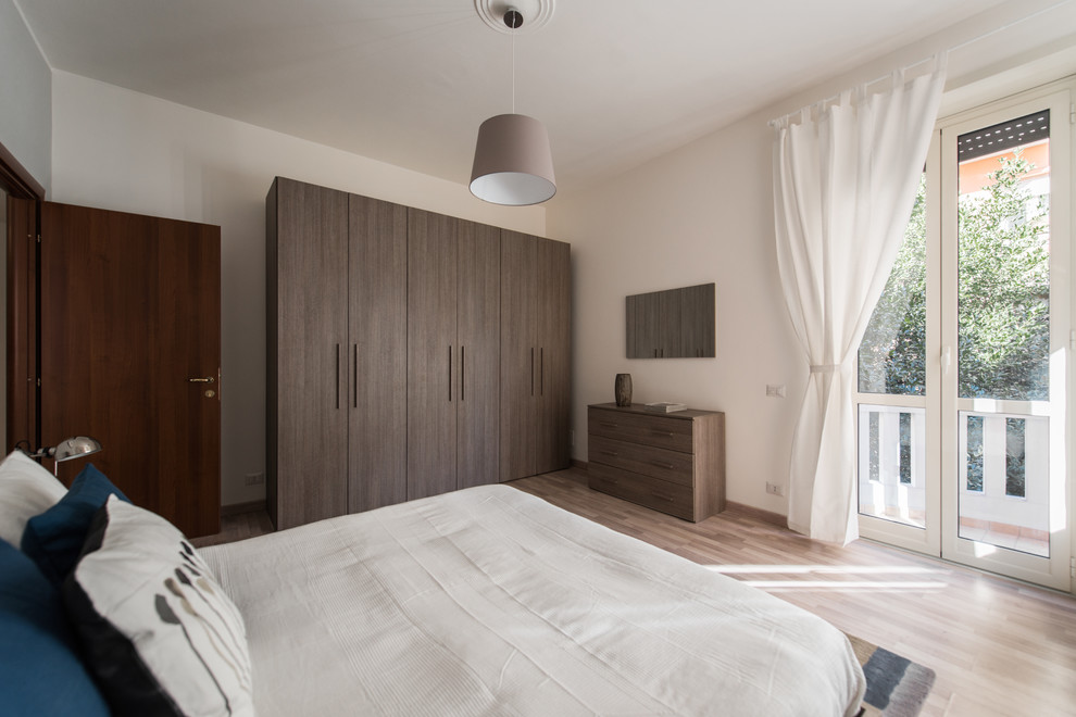 Mid-sized modern master bedroom in Rome with beige walls, light hardwood floors, no fireplace and beige floor.