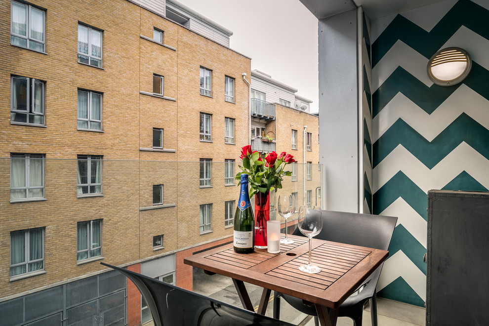 Small contemporary balcony in Surrey with a roof extension and feature lighting.