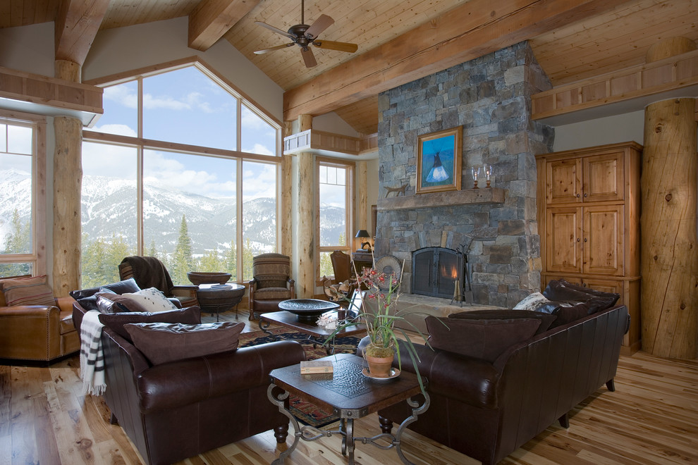 This is an example of a large country living room in Other with beige walls, light hardwood floors, a standard fireplace, a stone fireplace surround, a concealed tv and brown floor.