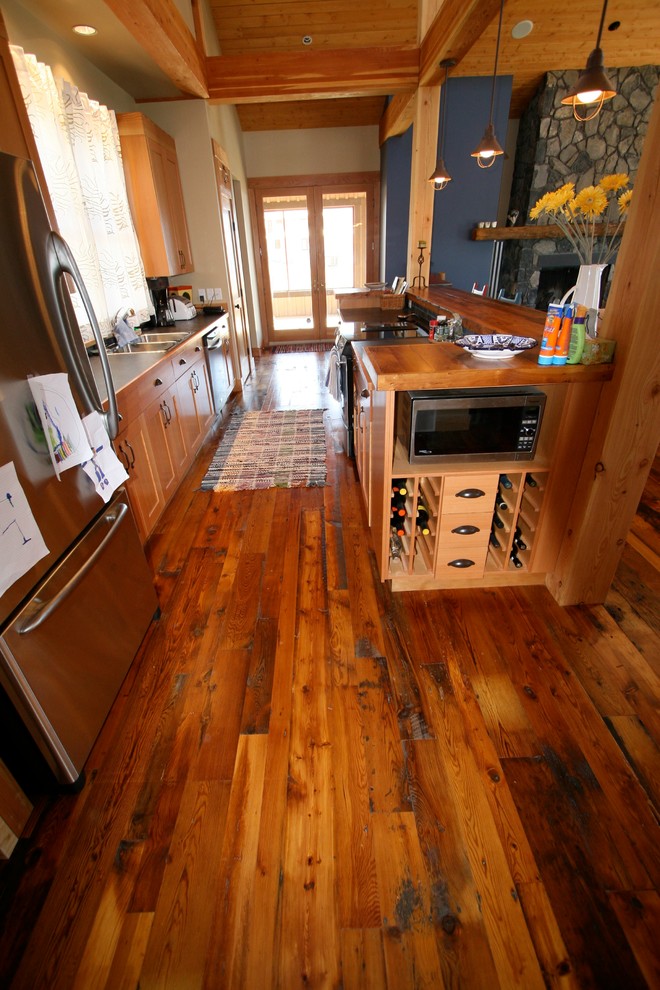 Open concept kitchen - small rustic galley dark wood floor open concept kitchen idea in Vancouver with a double-bowl sink, medium tone wood cabinets, wood countertops, stainless steel appliances and a peninsula