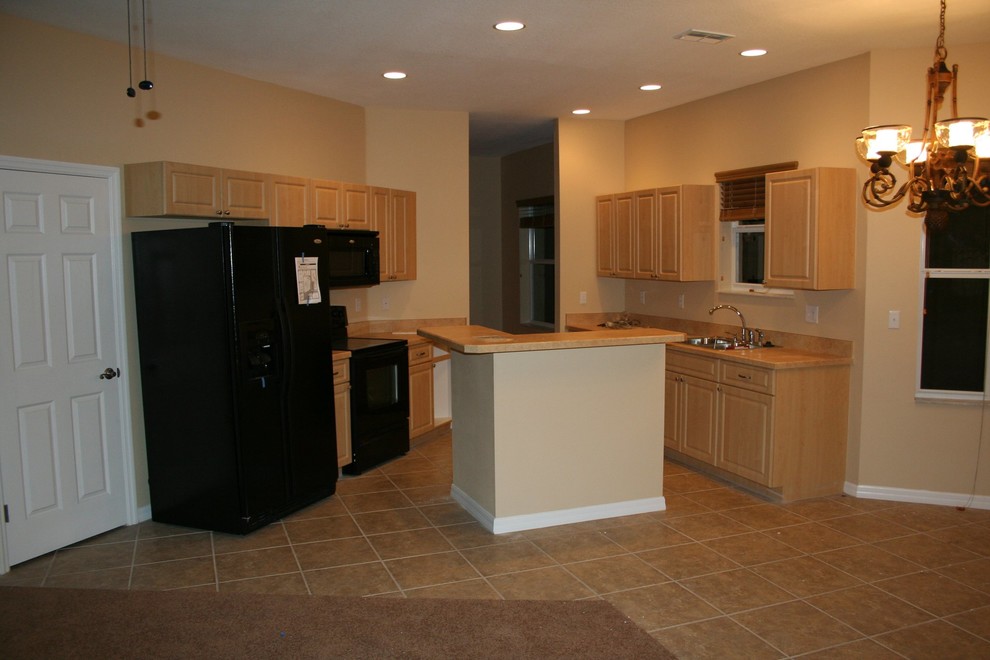 Mid-sized kitchen photo with light wood cabinets, laminate countertops, beige backsplash, black appliances and an island