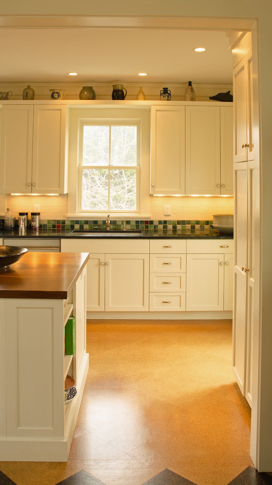 Inspiration for a large transitional l-shaped cork floor eat-in kitchen remodel in Boston with an undermount sink, shaker cabinets, white cabinets, soapstone countertops, green backsplash, ceramic backsplash, stainless steel appliances and an island