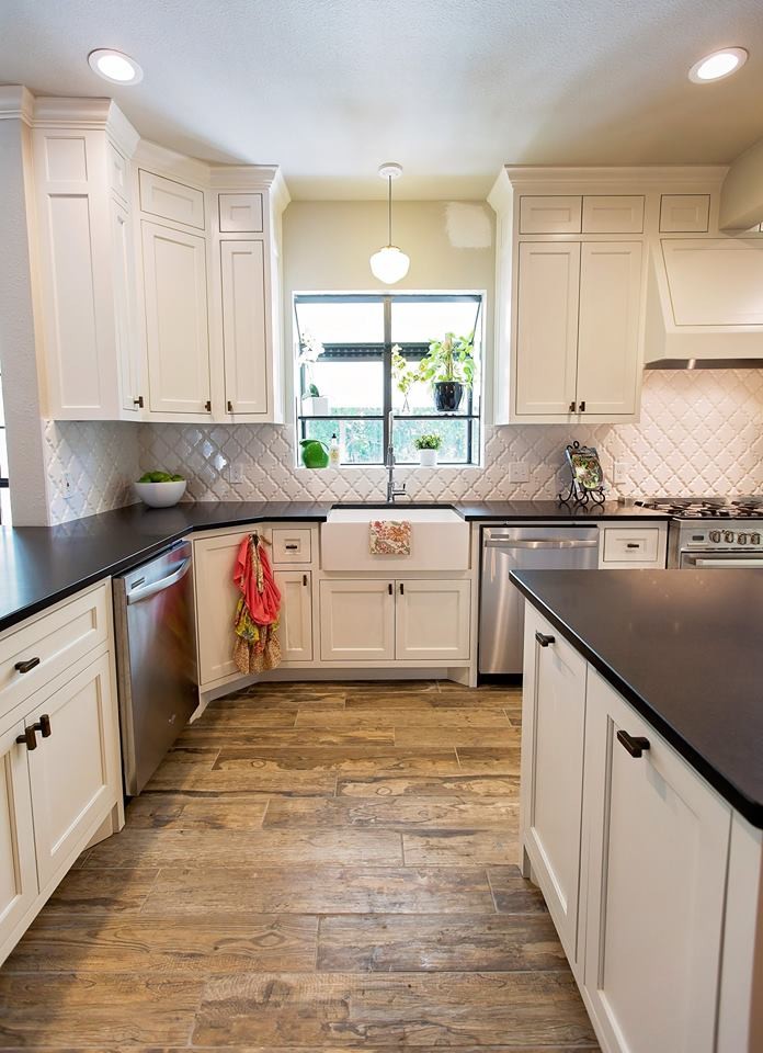 Photo of a large country u-shaped open plan kitchen in Orange County with a farmhouse sink, recessed-panel cabinets, white cabinets, quartz benchtops, white splashback, porcelain splashback, stainless steel appliances, light hardwood floors, with island and beige floor.