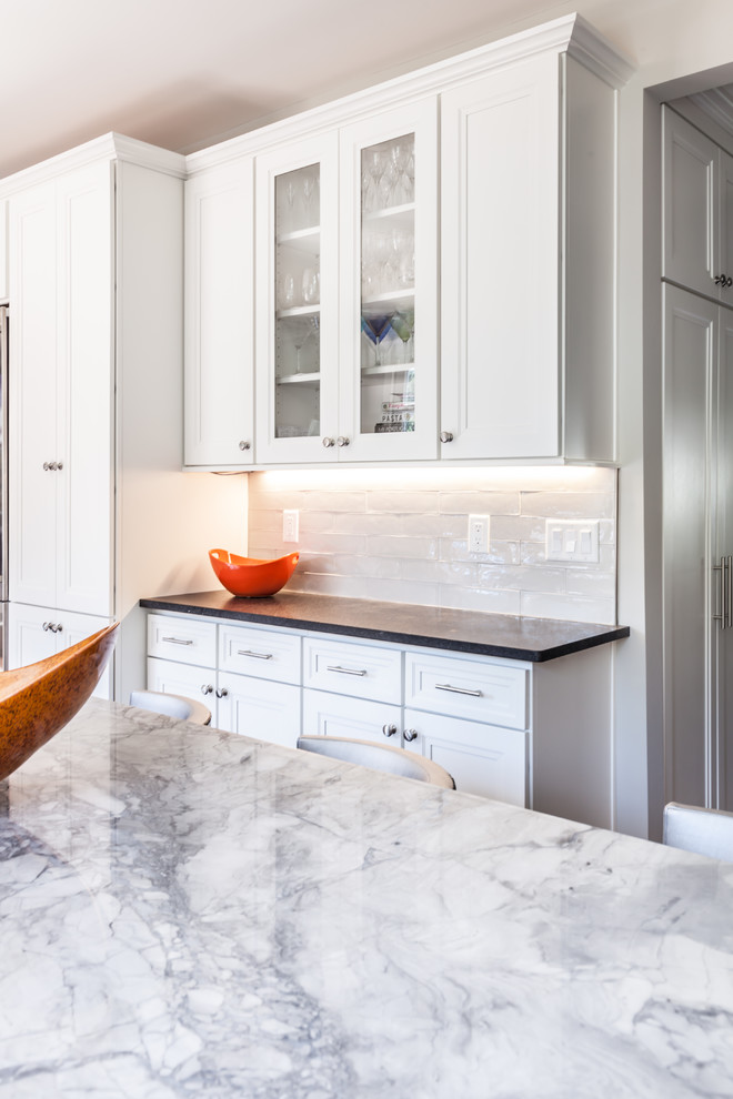 Inspiration for a large transitional u-shaped eat-in kitchen in New York with an undermount sink, recessed-panel cabinets, white cabinets, quartzite benchtops, white splashback, stainless steel appliances, with island, subway tile splashback, medium hardwood floors and brown floor.