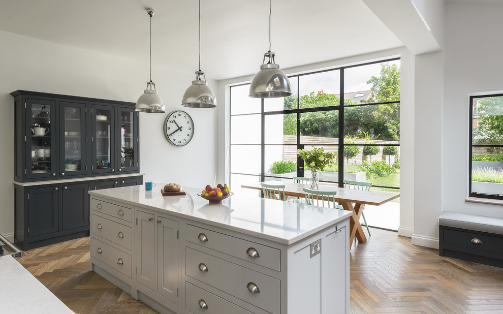 This is an example of a mid-sized traditional eat-in kitchen in London with shaker cabinets, dark wood cabinets, quartzite benchtops and with island.