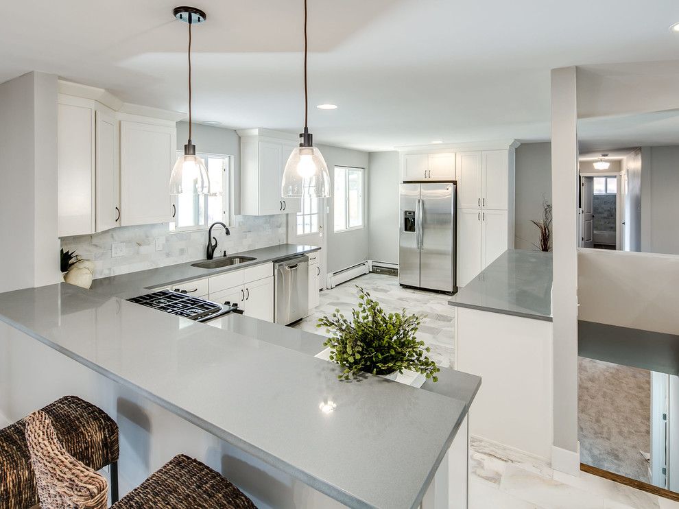 Eat-in kitchen - mid-sized transitional l-shaped marble floor eat-in kitchen idea with an undermount sink, shaker cabinets, white cabinets, white backsplash, stainless steel appliances, a peninsula, solid surface countertops and stone tile backsplash