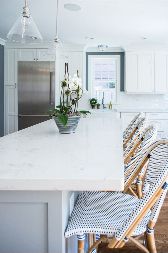 Large transitional l-shaped medium tone wood floor and brown floor open concept kitchen photo in Chicago with a farmhouse sink, recessed-panel cabinets, white cabinets, quartz countertops, white backsplash, subway tile backsplash, stainless steel appliances, an island and white countertops