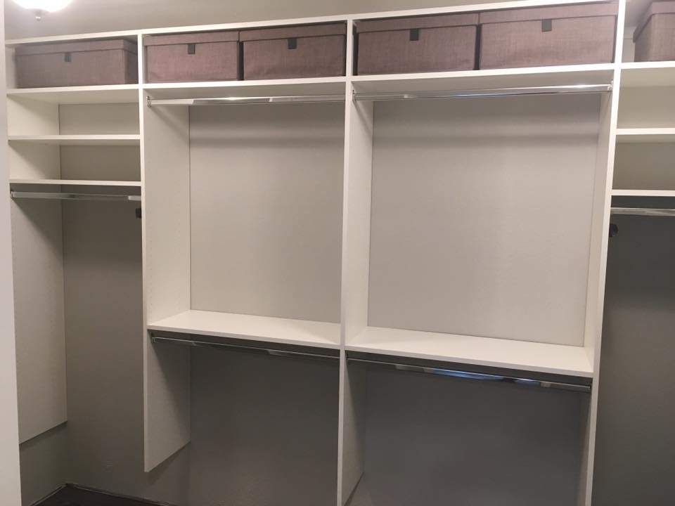 This is an example of a mid-sized contemporary gender-neutral walk-in wardrobe in Dallas with raised-panel cabinets, white cabinets, dark hardwood floors and brown floor.