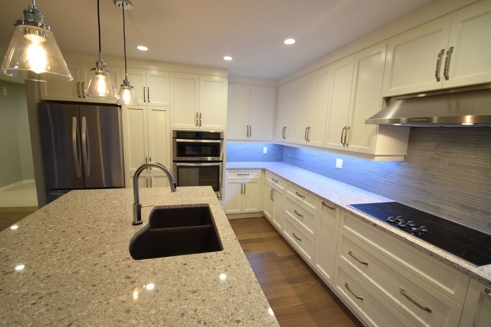 Eat-in kitchen - transitional l-shaped vinyl floor eat-in kitchen idea in Edmonton with a double-bowl sink, shaker cabinets, white cabinets, quartz countertops, gray backsplash, glass tile backsplash, stainless steel appliances and an island