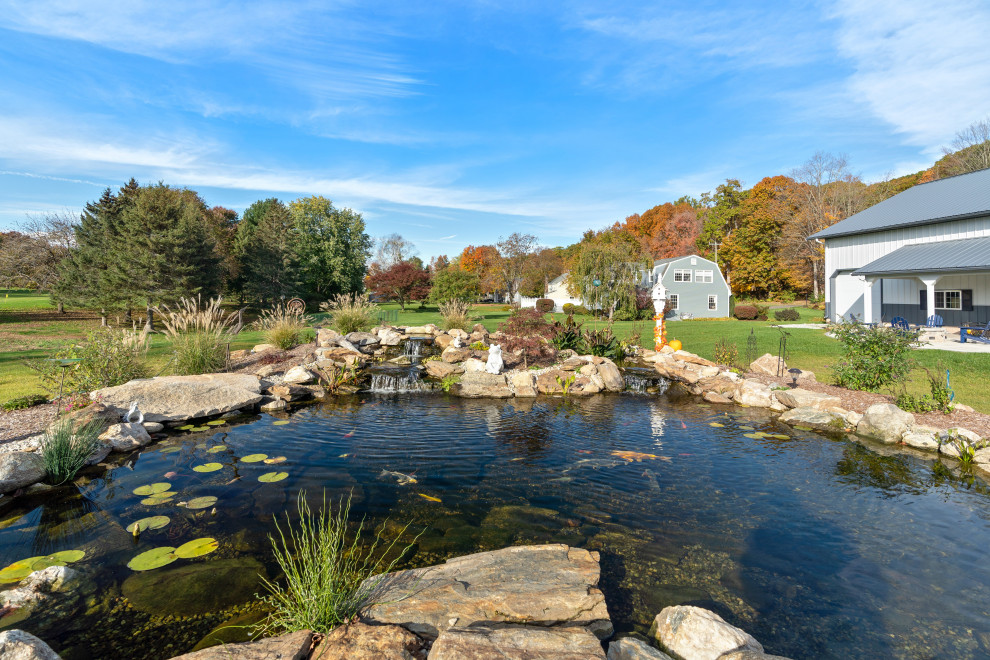 Idee per un grande laghetto da giardino country esposto in pieno sole dietro casa con sassi di fiume