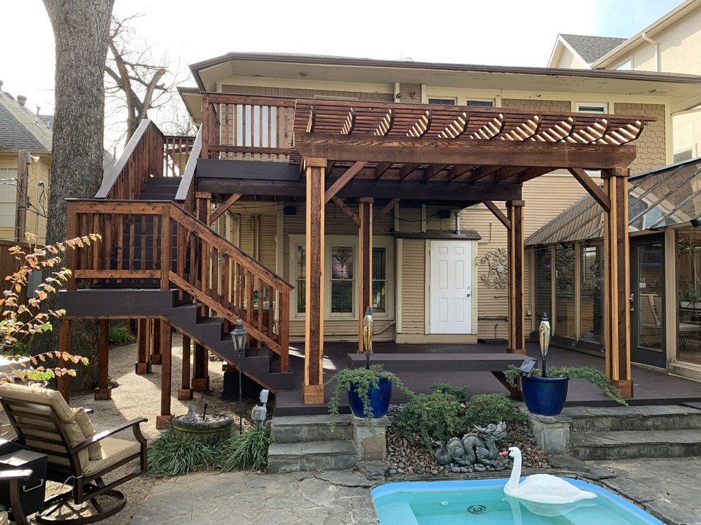 This is an example of a large country backyard deck in Dallas with a pergola.