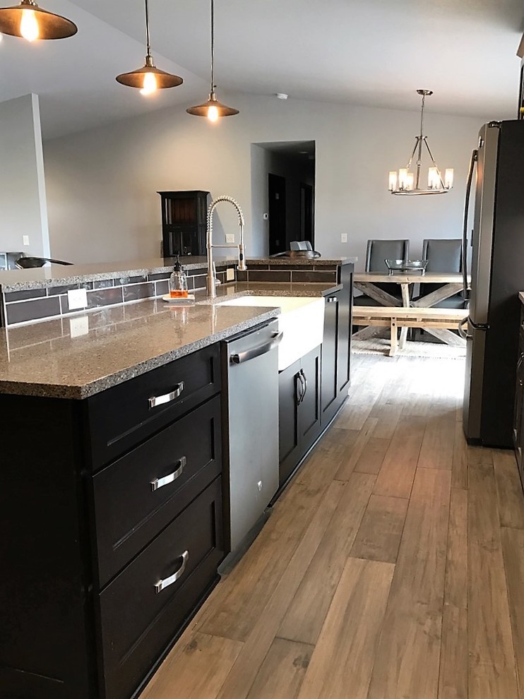 Inspiration for a mid-sized transitional single-wall light wood floor and brown floor open concept kitchen remodel with shaker cabinets, dark wood cabinets, multicolored backsplash, glass tile backsplash, stainless steel appliances, an island, a farmhouse sink and granite countertops
