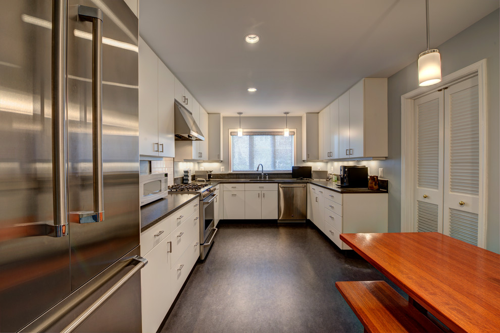 Example of a transitional l-shaped enclosed kitchen design in DC Metro with white cabinets, white backsplash, an undermount sink, flat-panel cabinets, subway tile backsplash, stainless steel appliances, no island and solid surface countertops