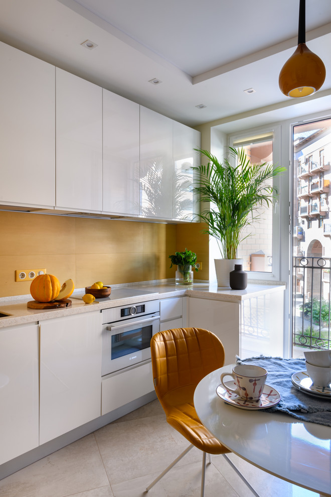 This is an example of a small contemporary l-shaped separate kitchen in Moscow with an undermount sink, white cabinets, solid surface benchtops, yellow splashback, white appliances, porcelain floors, no island, grey floor, flat-panel cabinets and white benchtop.