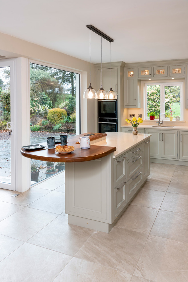 Inspiration for a mid-sized country l-shaped eat-in kitchen in Cork with a double-bowl sink, flat-panel cabinets, green cabinets, quartzite benchtops, beige splashback, stainless steel appliances, porcelain floors, with island, beige floor and beige benchtop.