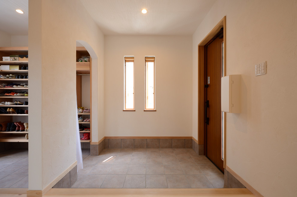 This is an example of a modern entry hall in Osaka with a single front door, a medium wood front door and grey floor.