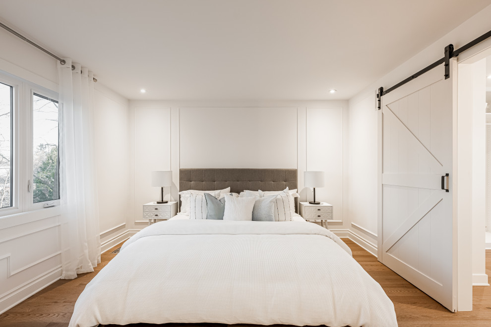 This is an example of a large modern master bedroom in Montreal with white walls, light hardwood flooring and beige floors.